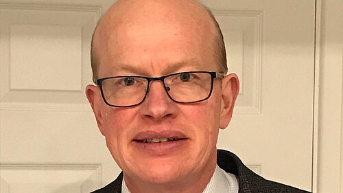 Paul de Kort is pictured wearing a suit, smiling and looking at the camera. 