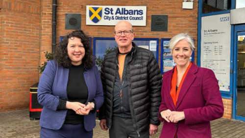 Victoria Collins MP, Councillor Paul de Kort, and Daisy Cooper MP (from left to right) are standing in front of the St Albans District Council building.