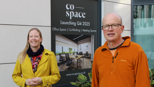 Councillors Helen Campbell and Paul de Kort are standing in the Jubilee Square development, in front of a posted announcing the launch of Co-Space St Albans.