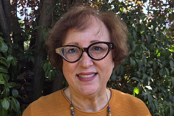 Lorraine is standing outside, smiling and looking directly at the camera.