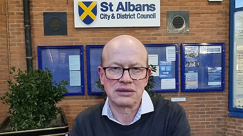Councillor Paul de Kort is standing in front of the St Albans District council building.