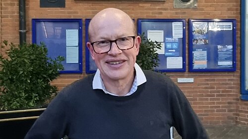 Councillor Paul de Kort is standing in front of the St Albans District Council building, smiling and looking directly at the camera.